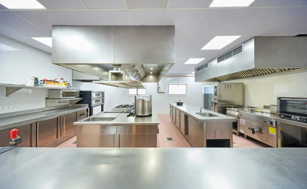 Cocina industrial del restaurante con acero inoxidable y campanas de extracción