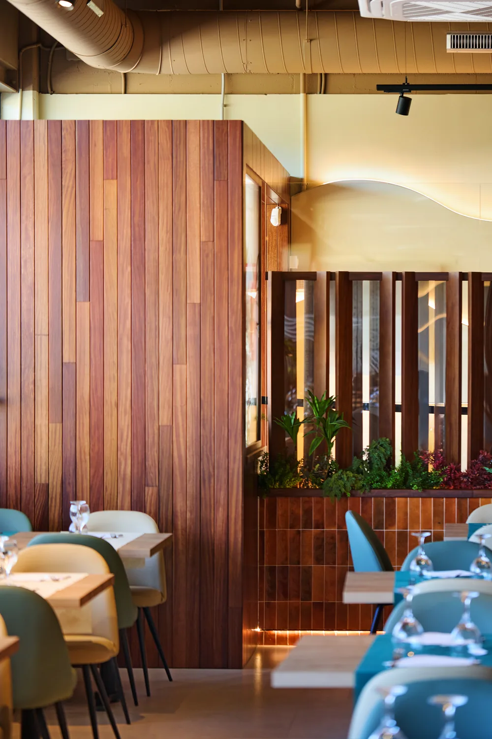 Revestimiento de madera de teca y celosía con vegetación en la sala