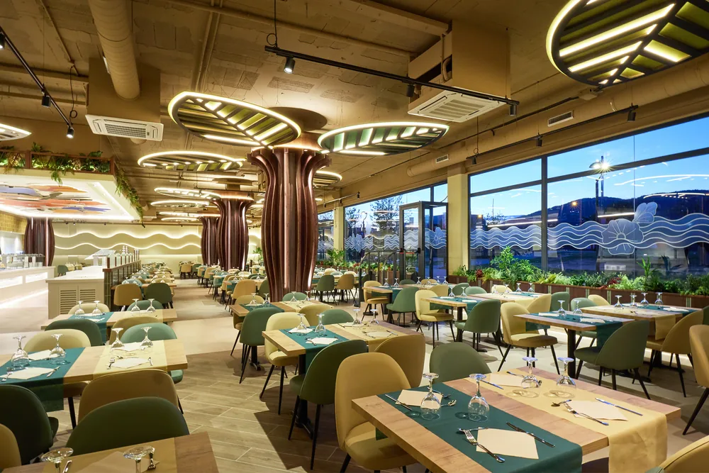 Sala del restaurante con luminarias suspendidas en forma de hoja junto al ventanal