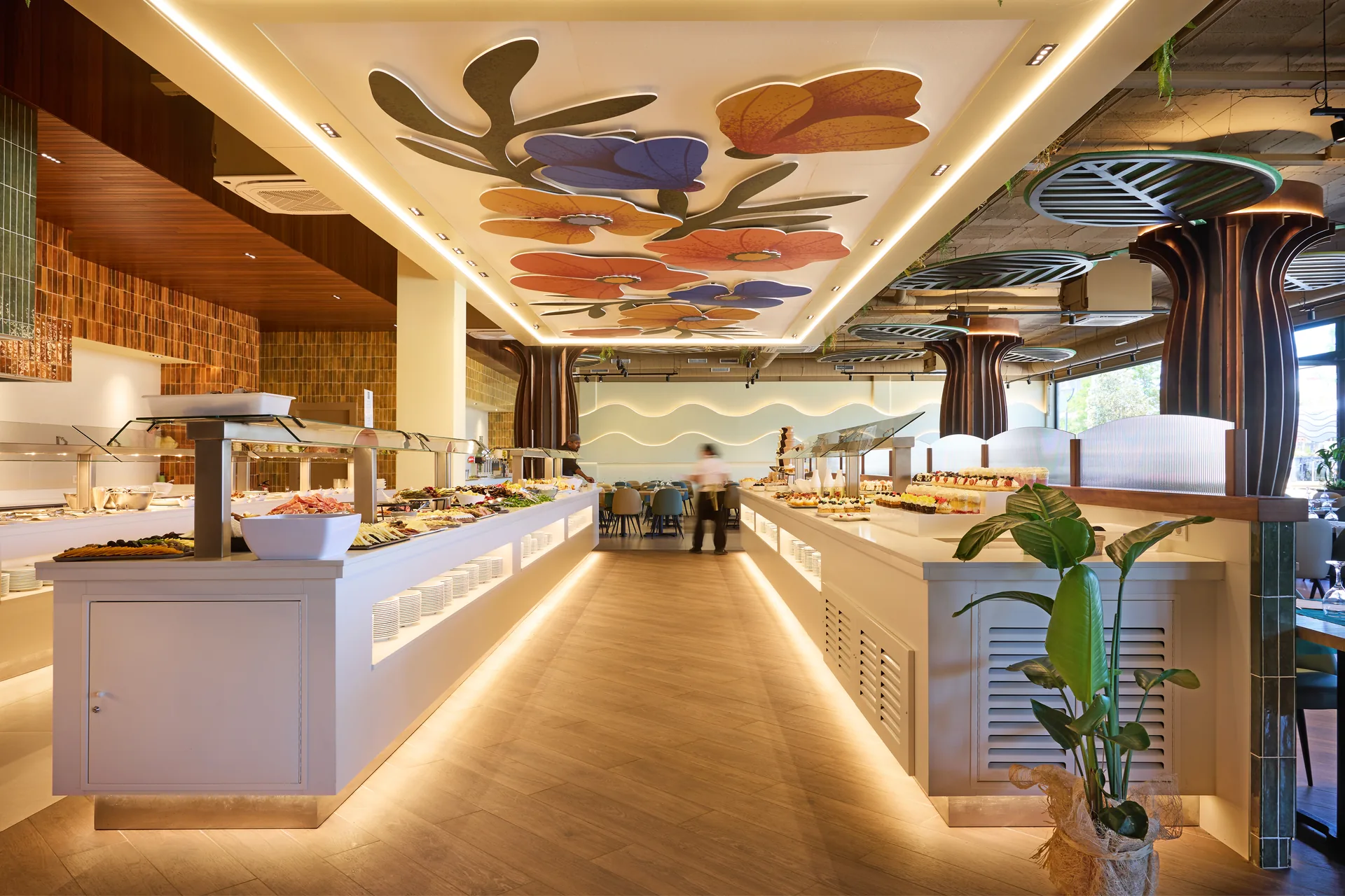 Zona de bufet del restaurante con columnas de madera en forma de árbol y techo floral